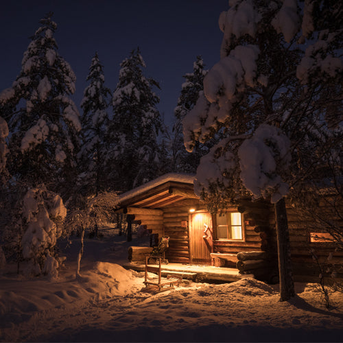 Cosy Winter Night Waxmelt – geurblokje van sojawas met muskus, eucalyptus, magnolia, viooltjes, neroli en sandelhout. Foto van houten chalet in besneeuwd winterbos.