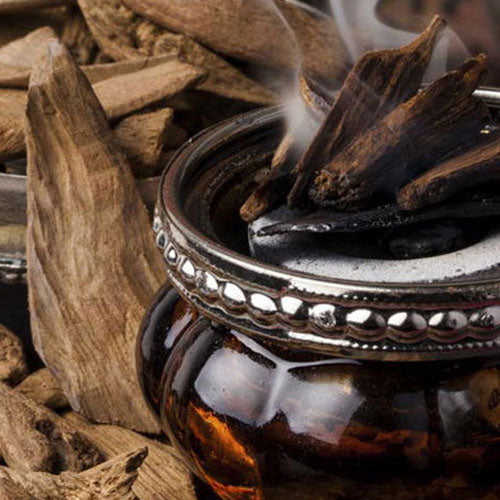 Arabian Oudh Waxmelt – geurblokje van sojawas met jasmijn, roos, oudh, amber, mos, tonka en musk. Foto van brandende oudh-hout in een oosterse houder, symbool voor luxe en mysterie.