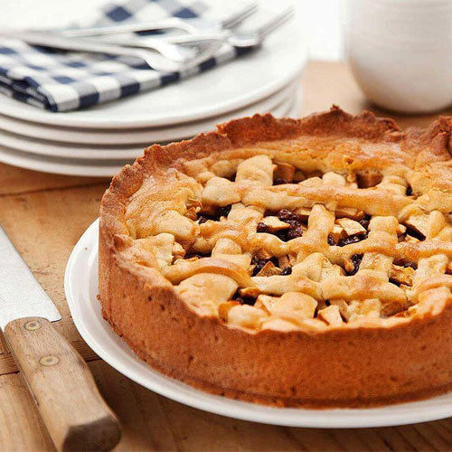 Appeltaart Waxmelt – geurblokje van sojawas met de geur van versgebakken appeltaart en kaneel. Foto van een ronde appeltaart op tafel met houten mes.