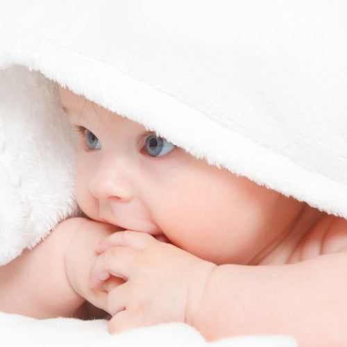 Baby Poeder Waxmelt – geurblokje van sojawas met zachte poederige babygeur. Foto van een baby onder een witte zachte deken.