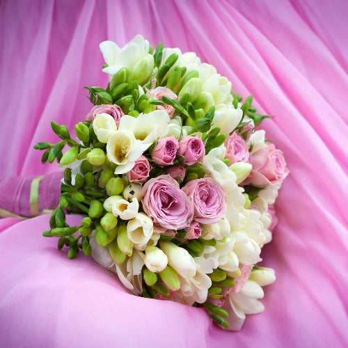 Freesia en Rose Waxmelt – geurblokje van sojawas met bloemige geur van freesia’s en pas gesneden rozen. Foto van boeket met witte freesia’s en roze rozen op roze achtergrond.