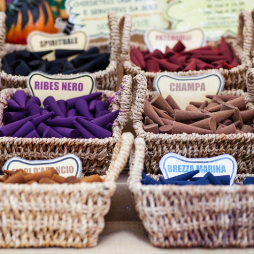 Nag Champa Waxmelt – geurblokje van sojawas met patchouli, sandelhout, jasmijn en vanille. Foto van mandjes vol kleurrijke wierookkegels, symbool voor spirituele geur