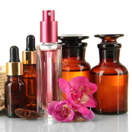 High Five Waxmelt – sojawas geurblokje met bloemige poederige parfumgeur van rozen, jasmijn en sandelhout. Foto van parfumflesjes en roze orchidee.