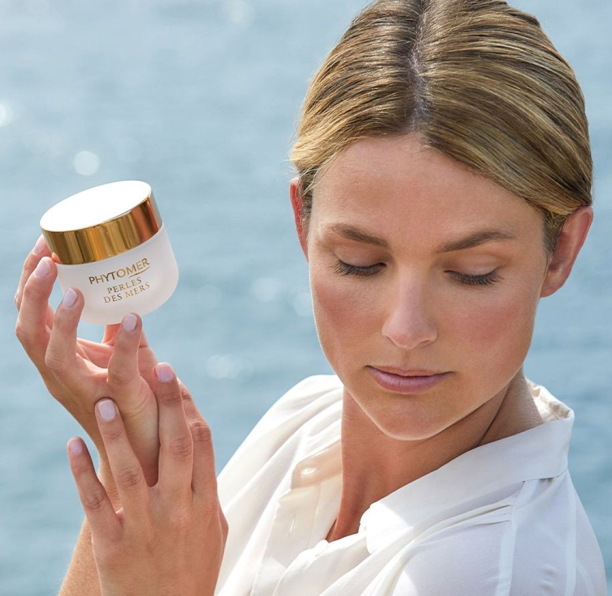 Model met Phytomer Perles des Mers crème bij zee – luxe mariene anti-aging verzorging