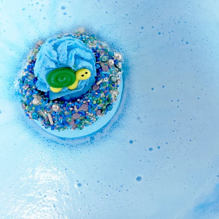 Bomb Cosmetics Turtle Eclipse of My Heart Bath Blaster met tropische kleuren en romige topping in bad