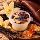 Hemelse Vanille & Leer Waxmelt van Pure Scents in een transparant potje met zachtgele sojawas, omringd door vanillebloemen, bruin leer en warme amber.